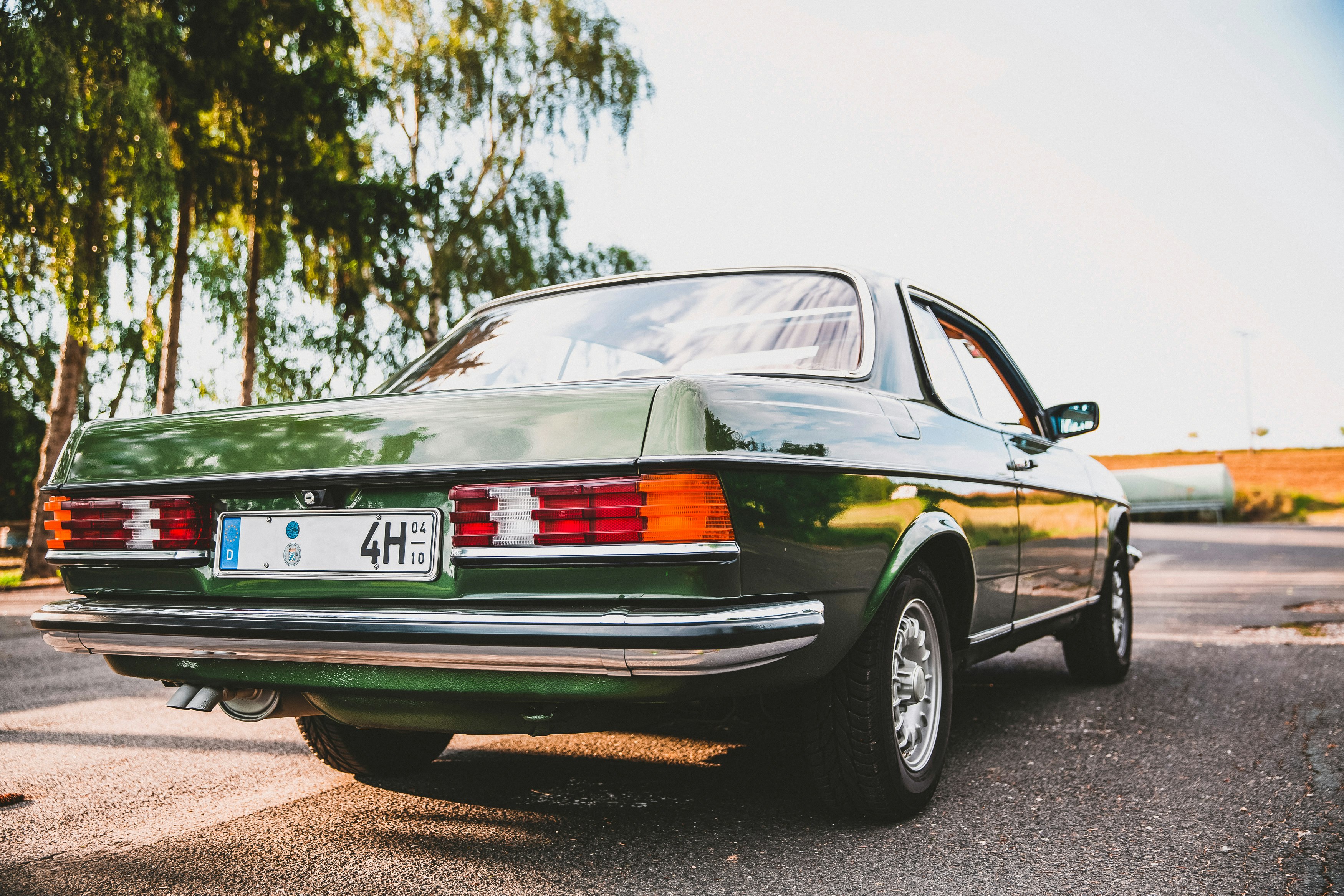 green sedan on gray asphalt road during daytime